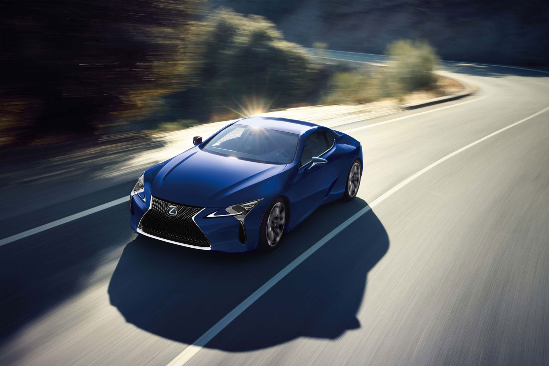 A Blue 2026 Lexus LC Hybrid driving down a winding road.