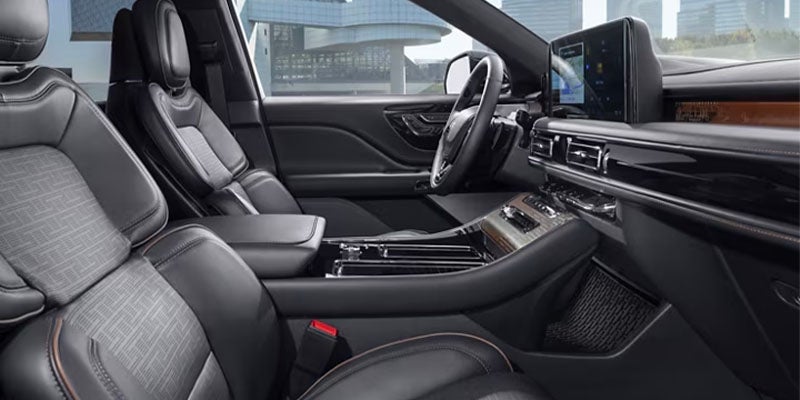 Luxurious car interior with black leather seats, large display, and wood trim on the dashboard and center console.