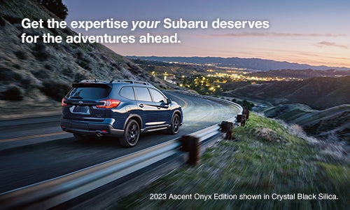 2023 Subaru Ascent Onyx Edition shown in Crystal Black Silica driving on a road on the side of a mountain.