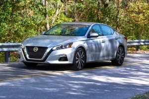 Silver 2022 Nissan Altima Sedan on the road surrounded by trees.