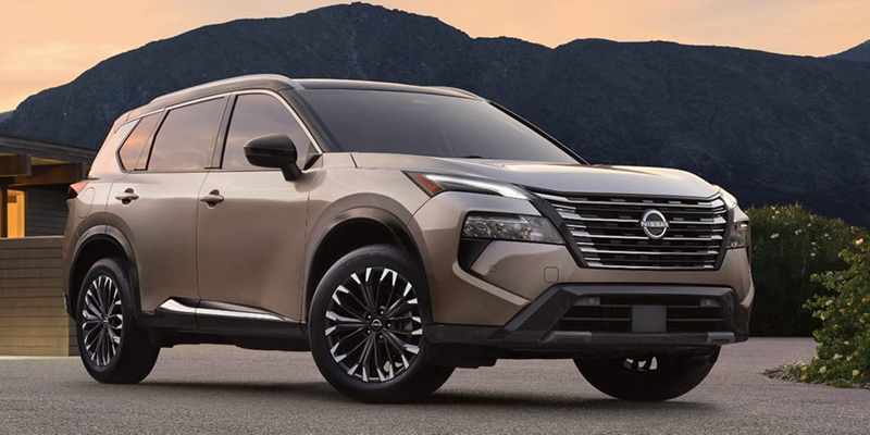 A Nissan Rogue parked in front of a mountain backdrop.