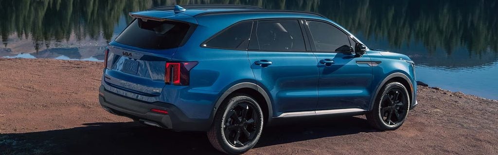 Blue Kia Sorento SUV parked beside a lake.