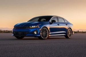 A dark blue 2022 Kia K5 parked in front of a desert.