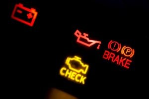 Image of the check engine, oil, battery and brake lights on the dashboard of a car.