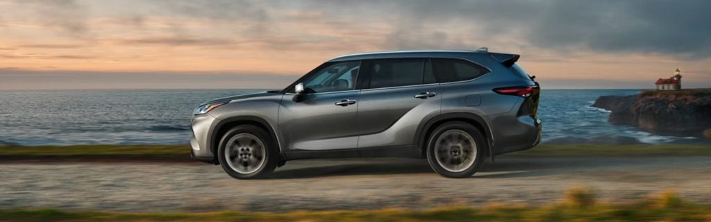 Toyota Highlander SUV driving along a coastal road near the ocean.