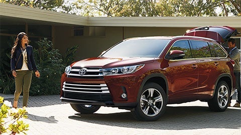 A vehicle owner walking towards their red Toyota SUV.