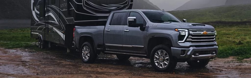 Gray Chevrolet Silverado 2500 HD towing a large travel trailer outdoors
