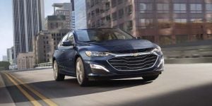 A blue 2022 Chevrolet Malibu driving through the city.