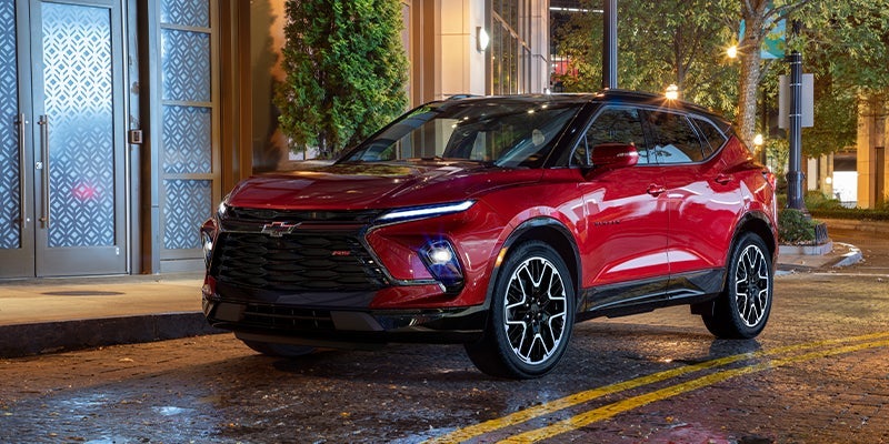 A red 2023 Chevy Blazer parked next to a building at night.