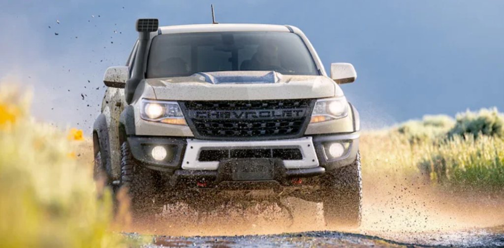 A silver 2022 Chevrolet Colorado driving on a dusty road.