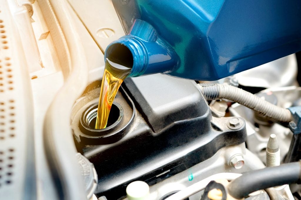 Pouring engine oil into a car engine.