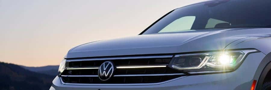 Close of of a 2022 Tiguan's LED headlights in front of an evening sky
