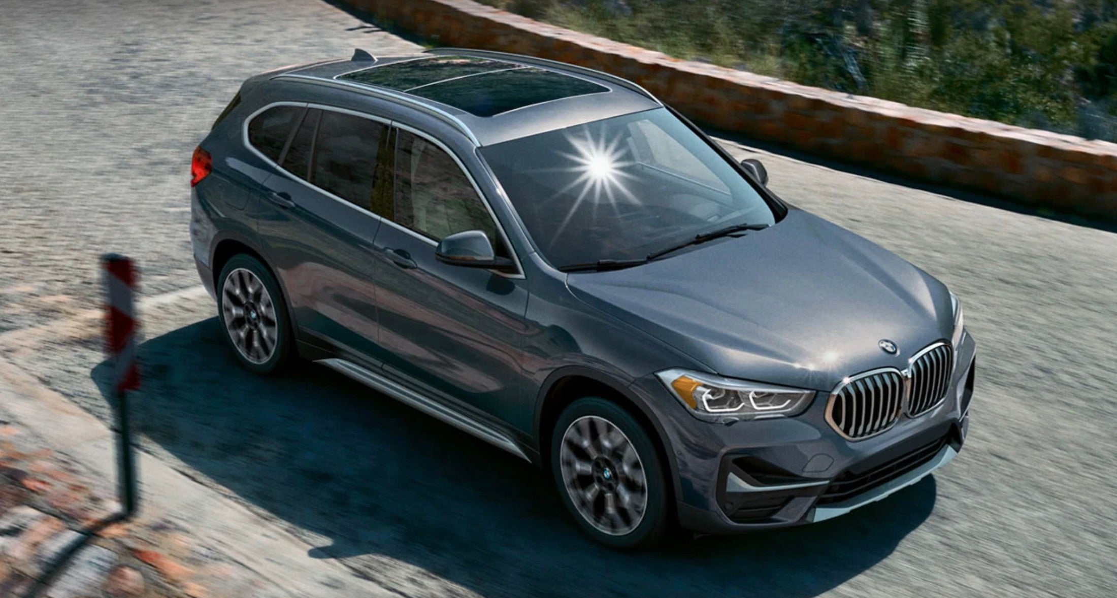 2022 BMW X1 in gray driving down the road at a high speed.