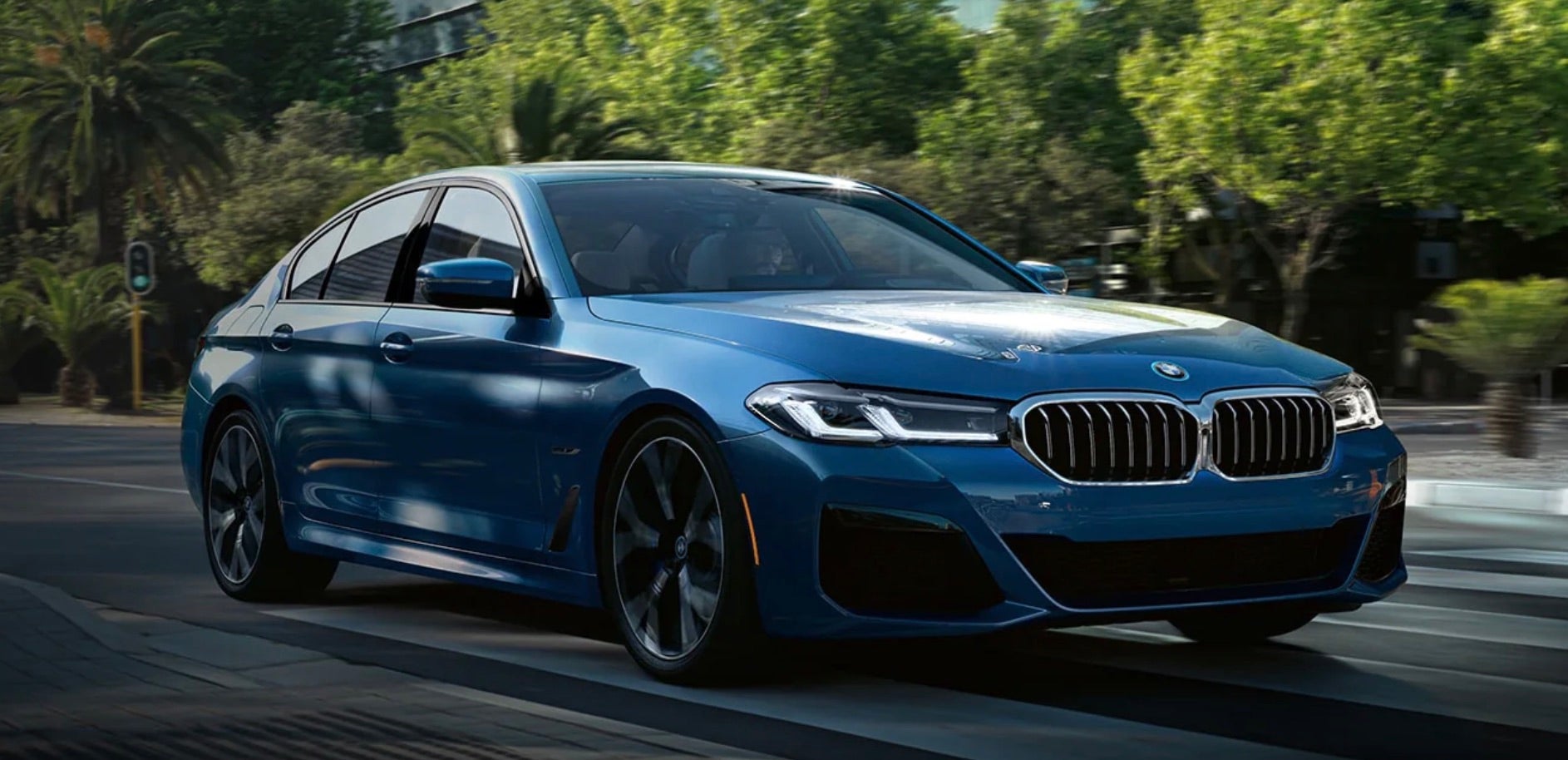Blue 2022 BMW 5 Series driving along the topical landscape of Florida.