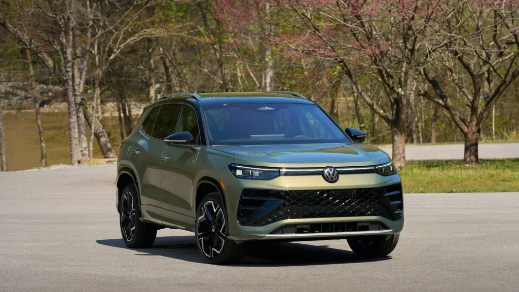 2026 Volkswagen Tiguan SEL R-Line Turbo green SUV parked near trees with front grille view.