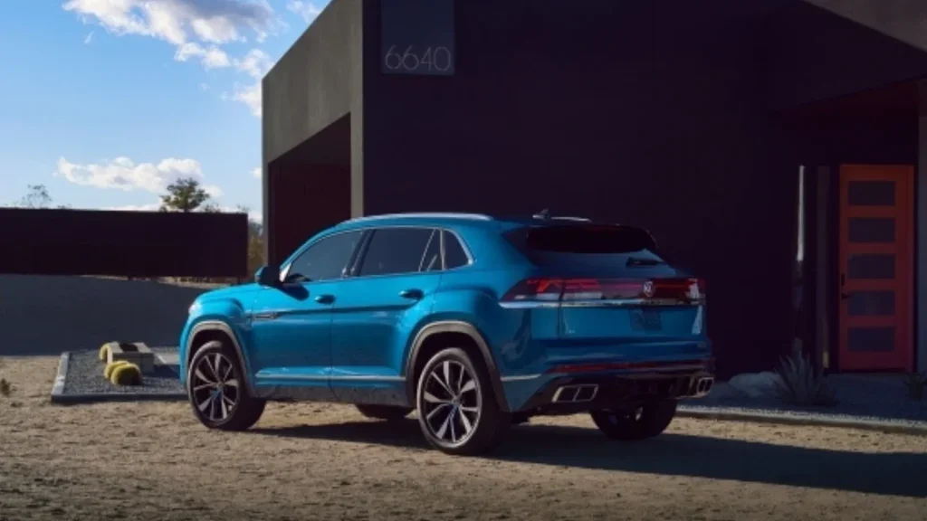 2026 Volkswagen Atlas Cross Sport blue SUV parked outside modern home with rear profile view.