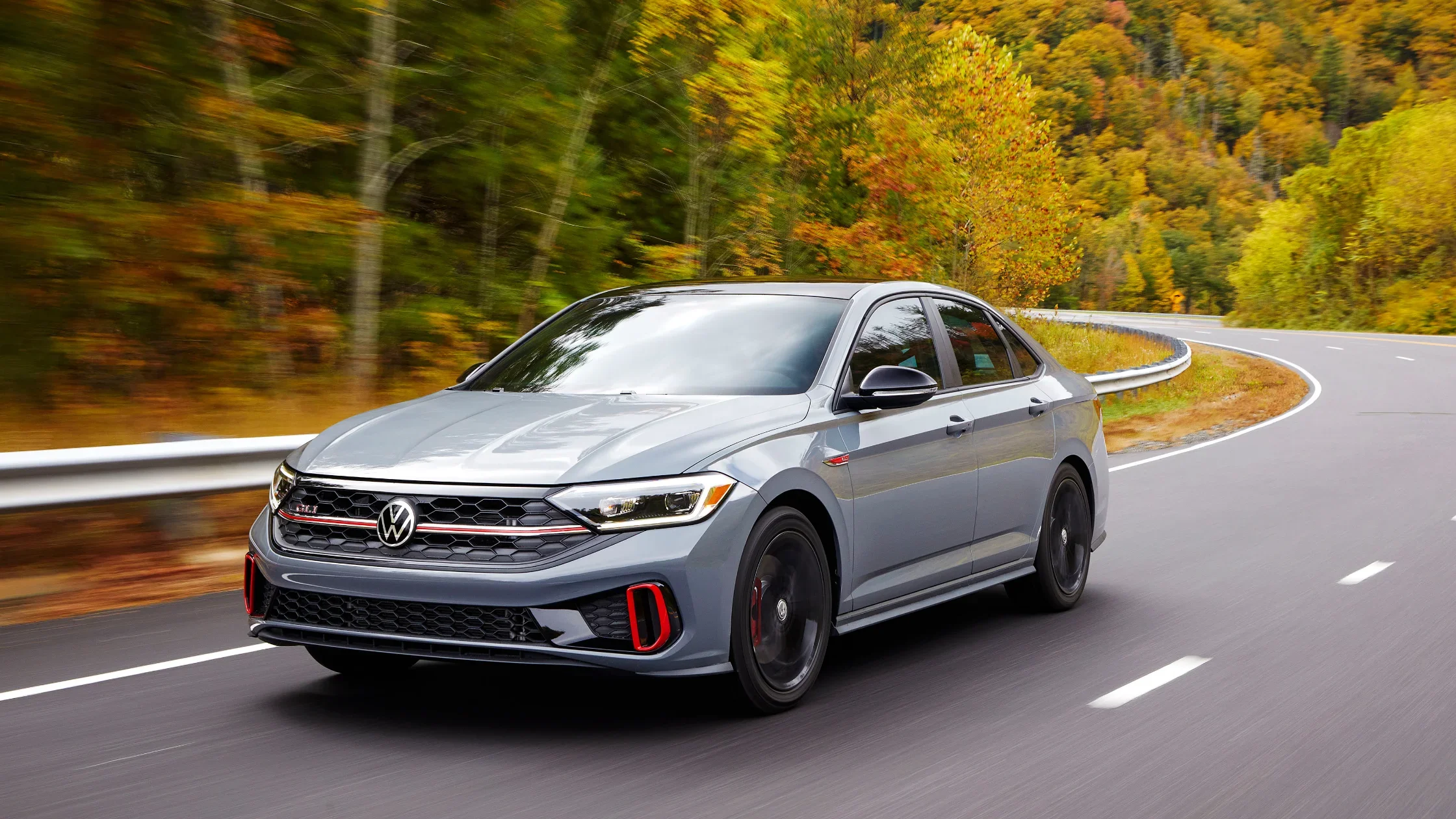 2024 Volkswagen Jetta GLI driving through vibrant autumn landscapes.