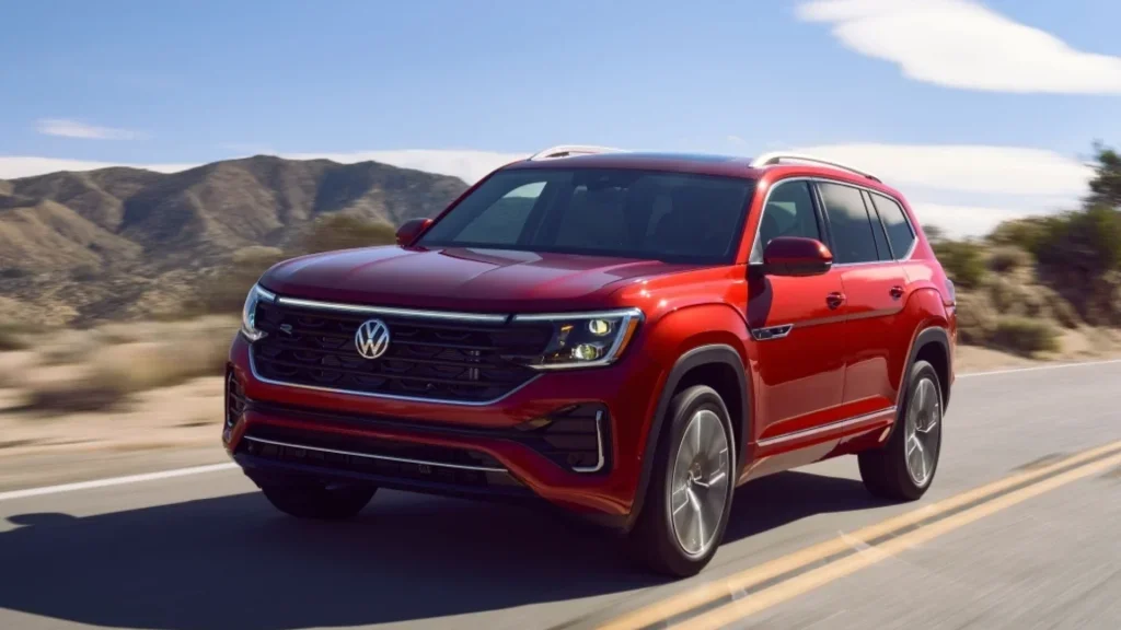 2026 Volkswagen Atlas red SUV driving on mountain road with front grille and LED headlights.