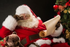 Portrait of happy Santa Claus reading Christmas letter or wish l