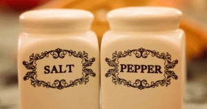 A pair of collectible white salt and pepper shakers with black script and designs