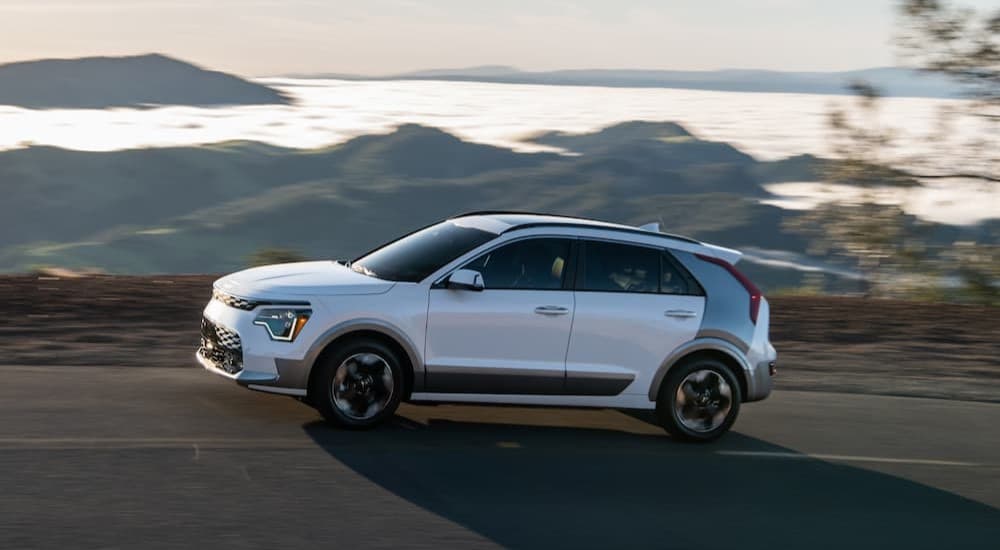 A white 2023 Kia Niro EV driving to a used Kia dealer.