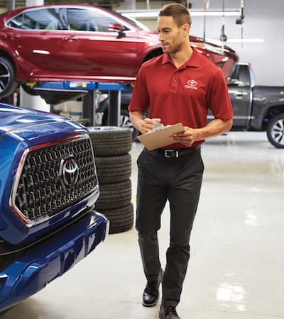 A Toyota service technician checking over a blue Toyota SUV