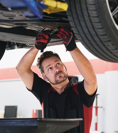 A Toyota service technician working under a vehicle on an oil change