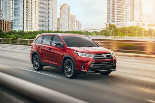 A red 2019 Toyota Highlander drving down a city street