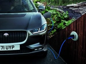 Front view of Jaguar I-Pace in a home driveway with the charging cable plugged in