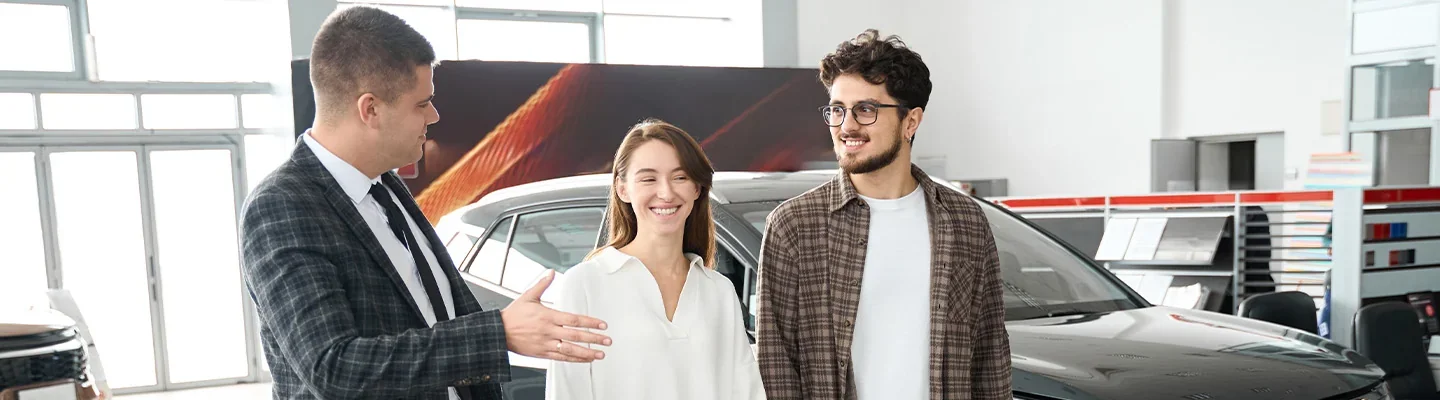 Couple speaking with salesman in dealership