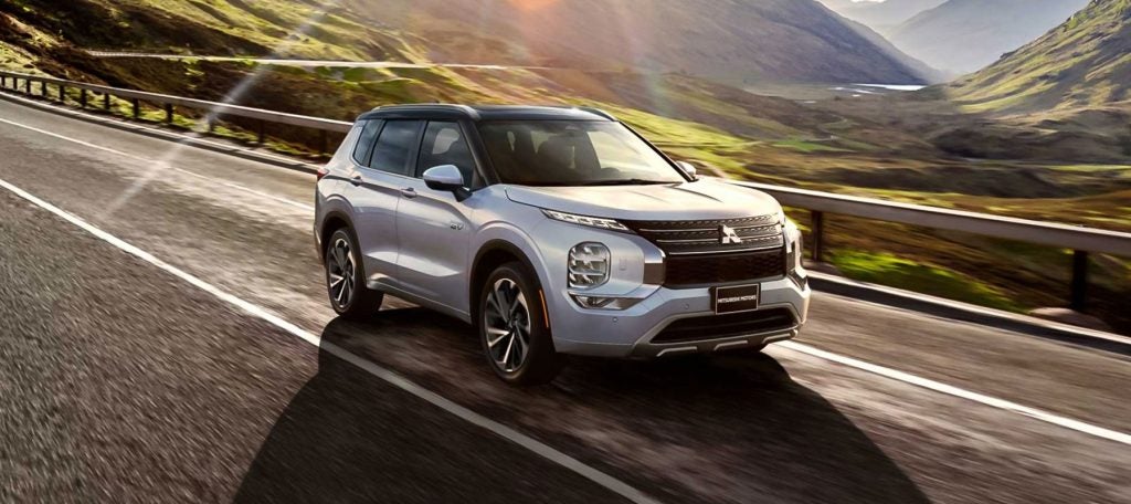Silver Mitsubishi SUV driving along a scenic mountain road, capturing the beauty of the surrounding nature.
