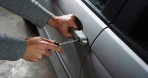 Burgler breaking into a car