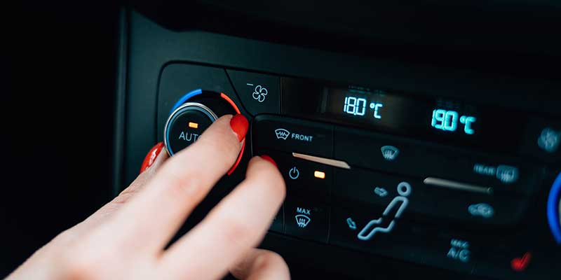 Adjusting the climate control dial on a car dashboard.