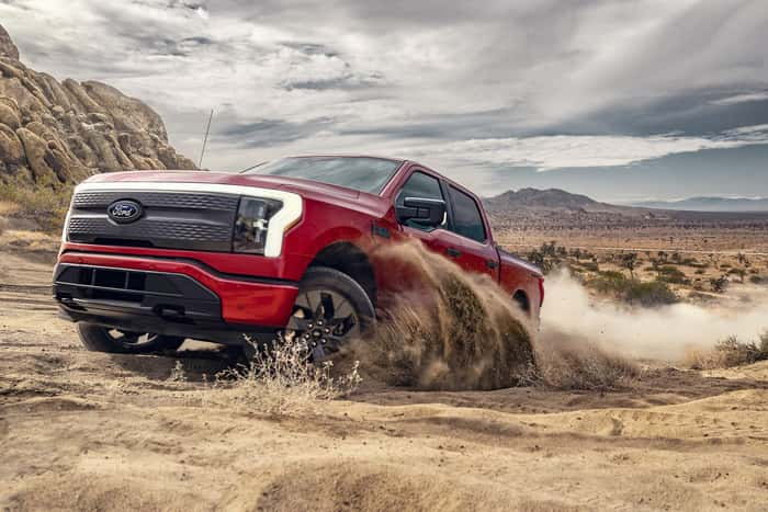 Red Ford F-150 Lightning driving in the sand