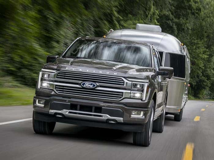 Gray Ford F-150 driving on the road towing a trailer