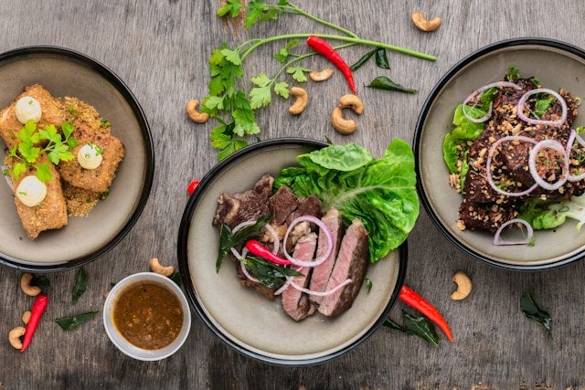 Three plates of Asian food on wood table