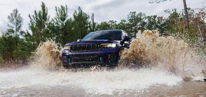 Blue Jeep Grand Cherokee driving through the water