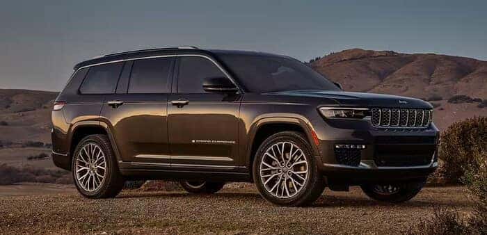 Jeep Grand Cherokee parked on dirt in front of mountains