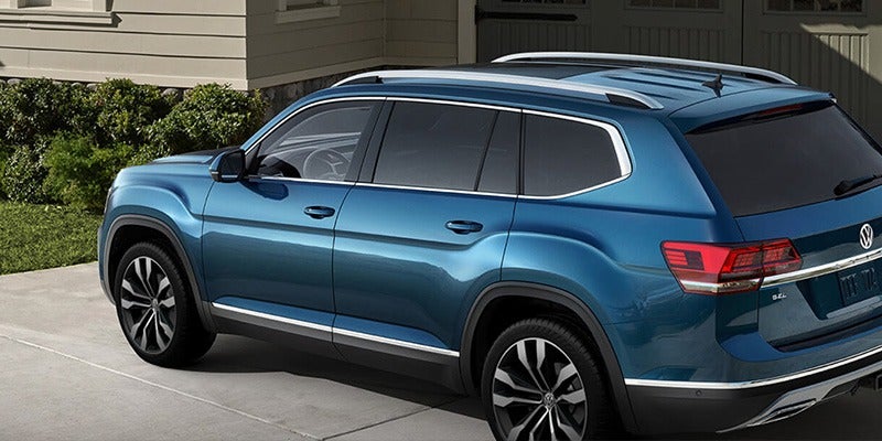 side view of a blue 2020 Volkswagen Atlas parked in a driveway of a home