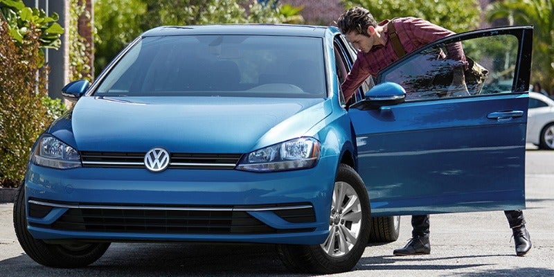 guy leaning into the drivers side door of his blue 2020 Volkswagen Golf 