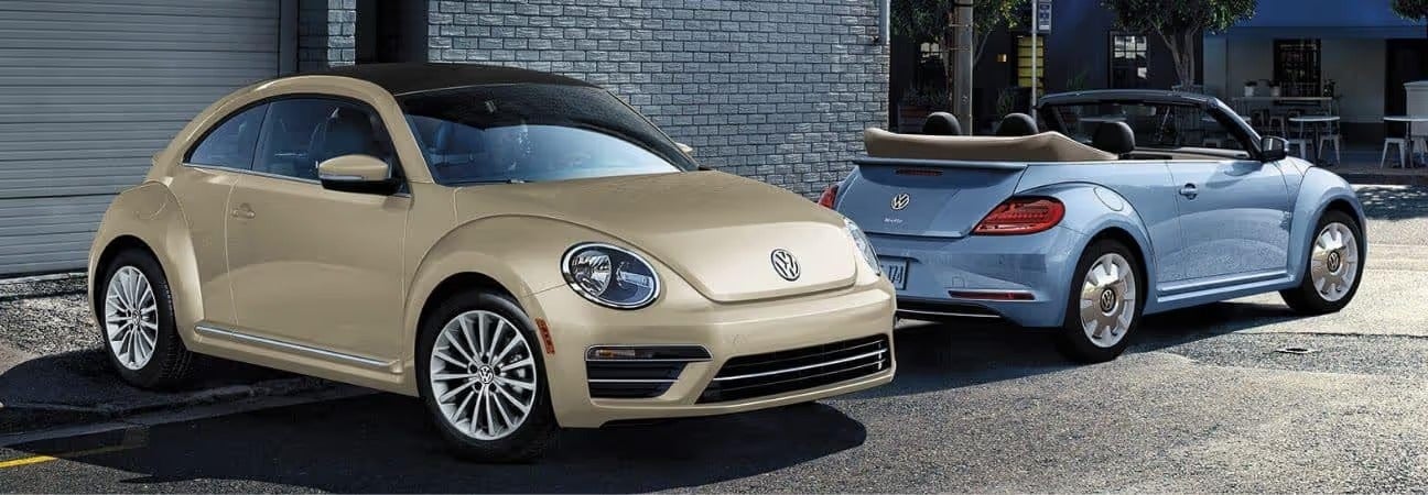 a tan and baby blue Beetle parked in front of a brick building