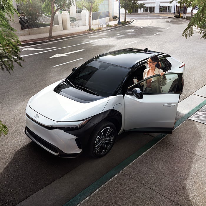 The All-New Toyota Electric Car: The Toyota bZ4X BEV at Bennett Toyota of Lebanon | Woman Getting Into Driver's Side of White Toyota bZ4X BEV Street Parked in City