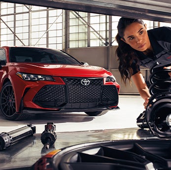 Basic Car Maintenance and Servicing Checklist | Bennett Toyota of Lebanon | Toyota Mechanic grabs new shocks with Avalon parked in background