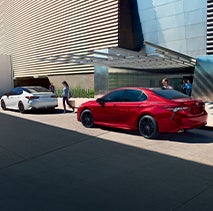 Model Features of the 2022 Toyota Camry at Bennett Toyota of Lebanon | Two Camrys parked outside in downtown day