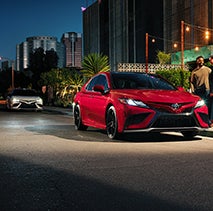 Model Features of the 2022 Toyota Camry at Bennett Toyota of Lebanon | Two Camrys parked outside in downtown at night