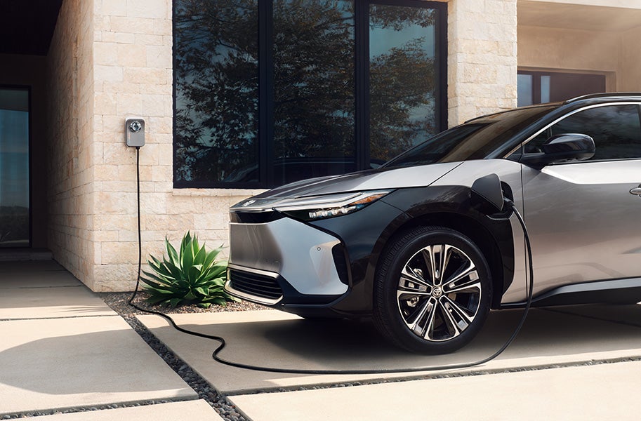 The All-New Toyota Electric Car: The Toyota bZ4X BEV at Bennett Toyota of Lebanon | Silver Toyota bZ4X BEV Parked Next To House While Charging