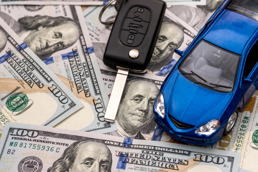 Keys to the car and car that are lying on 100 dollar bills