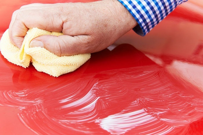 Close Up Of Hand Polishing Car Hood Using Cloth