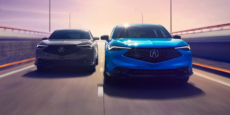 Two Acura SUVs driving side by side on a highway at sunset.