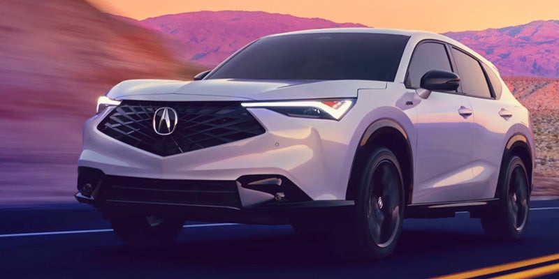 White Acura SUV driving on desert road at sunset